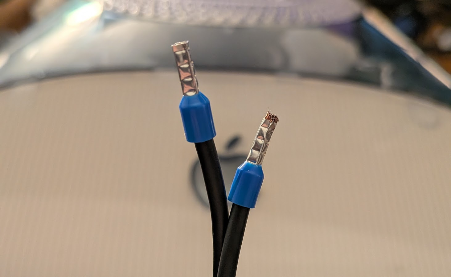 a black wire with blue ferrules on the ends, twisted and set on top of the mac by the apple logo