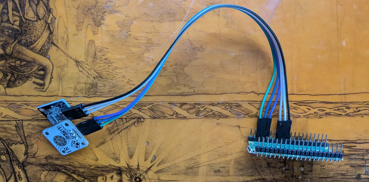 a raspberry pi pico with blue, green, purple, white, grey, and black jumper wires connected to an infrared transmitter and an infrared receiver